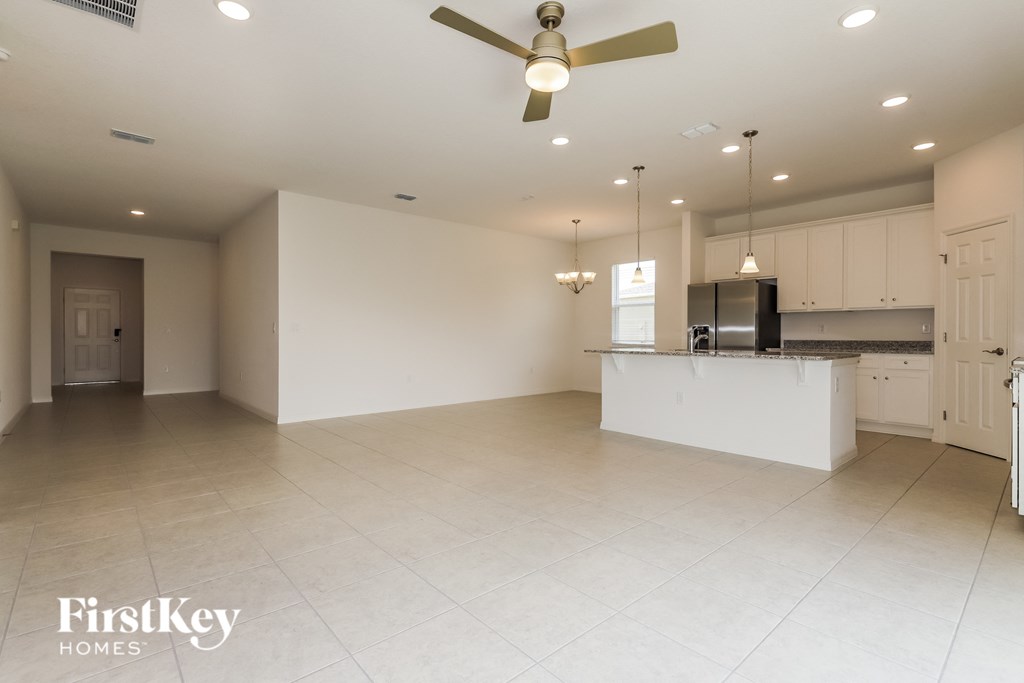 an empty kitchen and living room with a ceiling fan