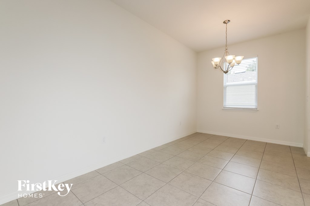 the dining room of a home with white walls and a tiled floor