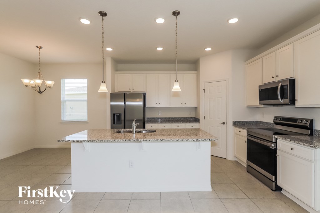 a kitchen with white cabinets and a marble counter top