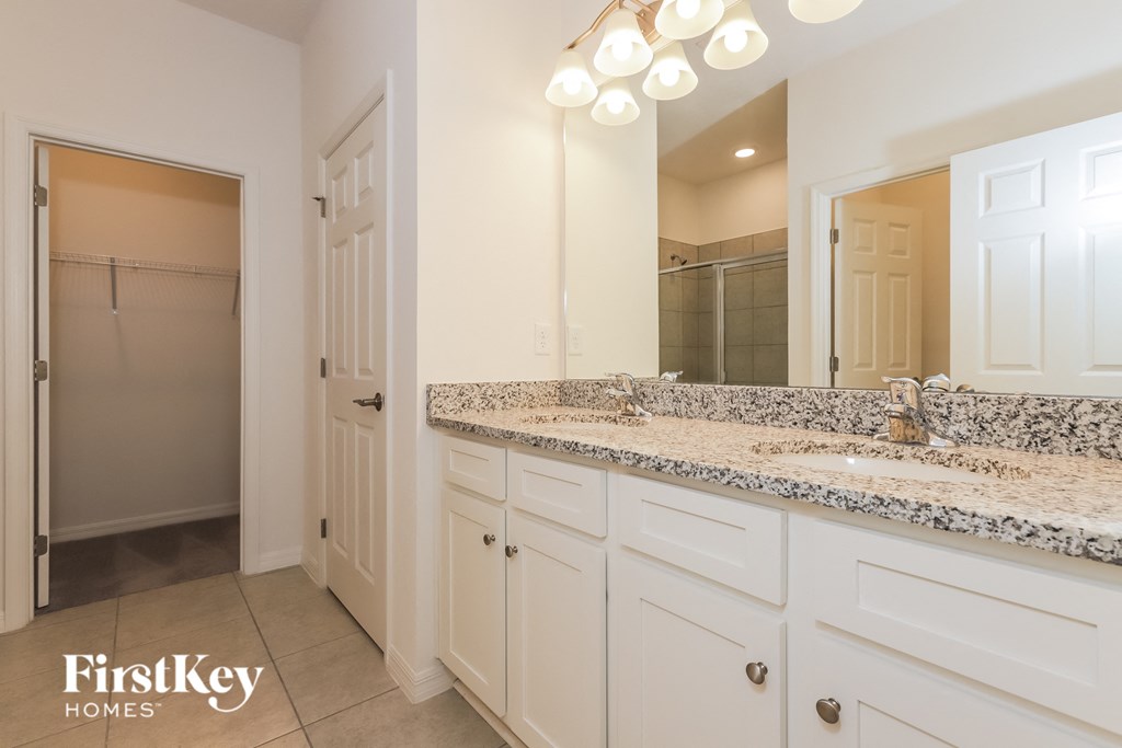 a bathroom with white cabinets and granite counter tops and a large mirror
