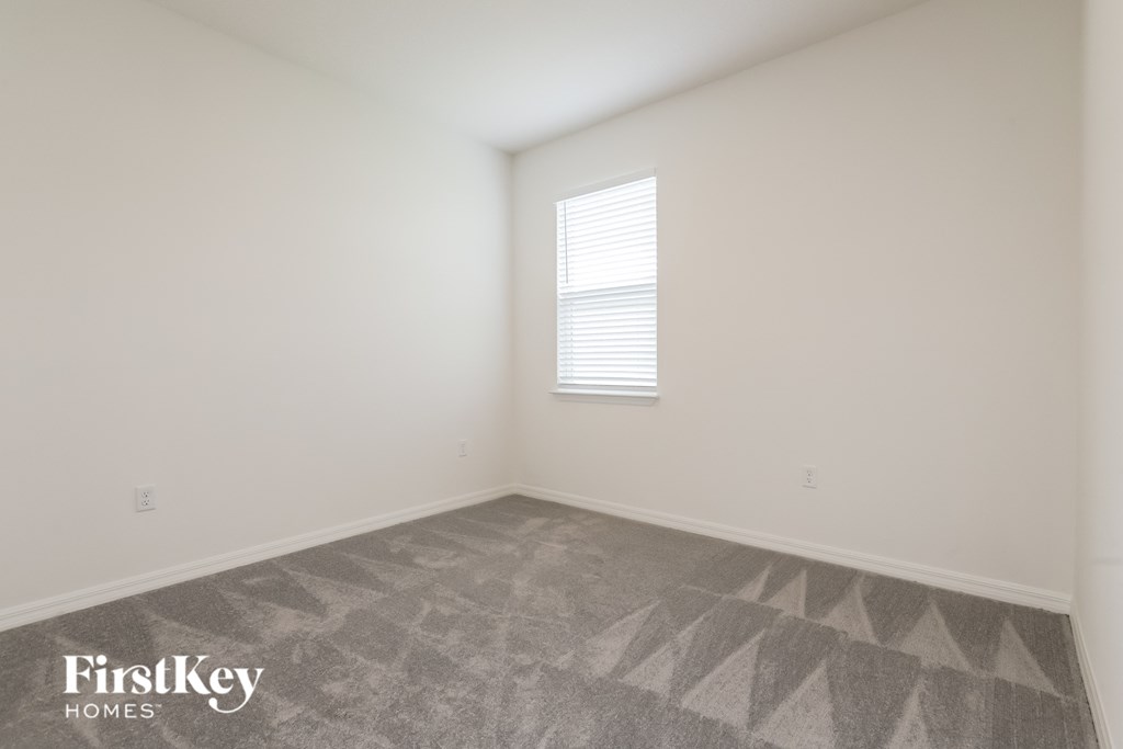 the living room of a home with white walls and a window