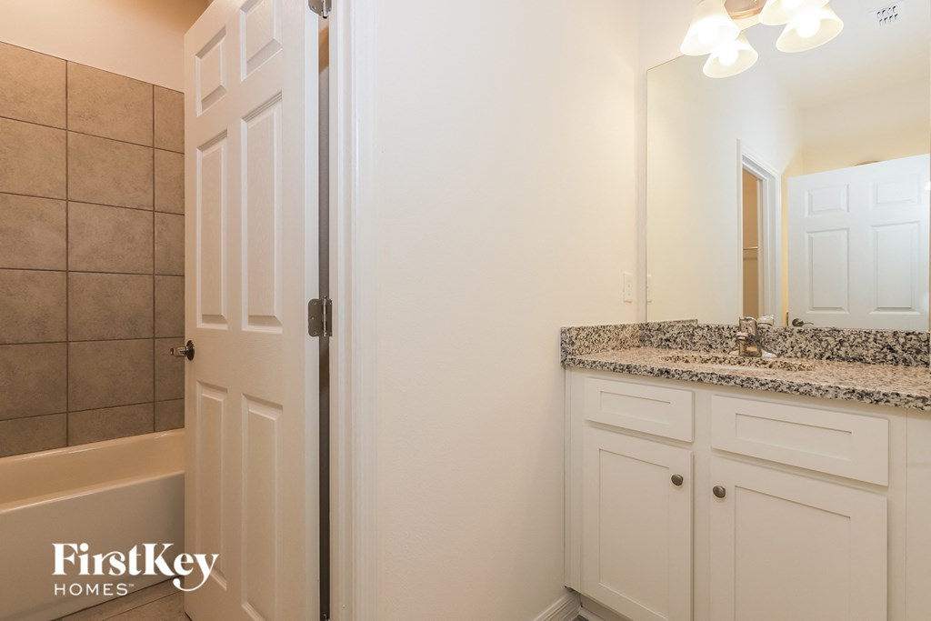 a bathroom with white cabinets and a shower and a sink