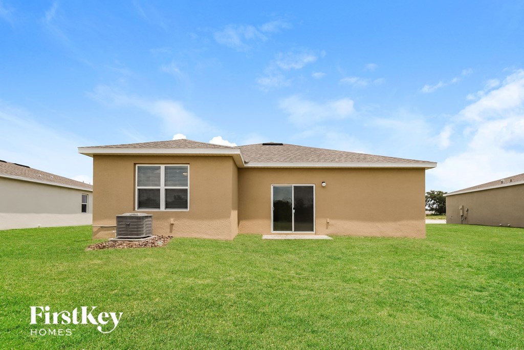 a beige house with a green lawn and a blue sky