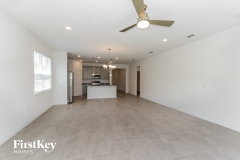A spacious, empty room with a ceiling fan and a chandelier.