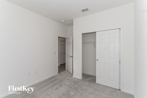 A white bedroom with a door and a closet.