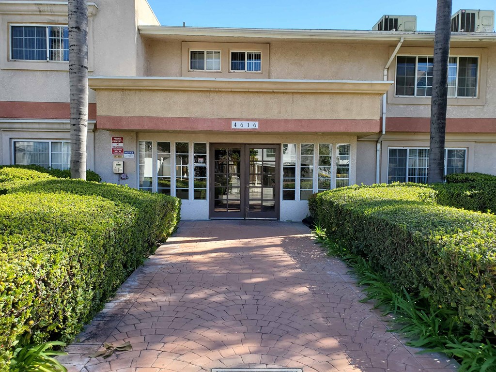the entrance to a building with hedges in front of it