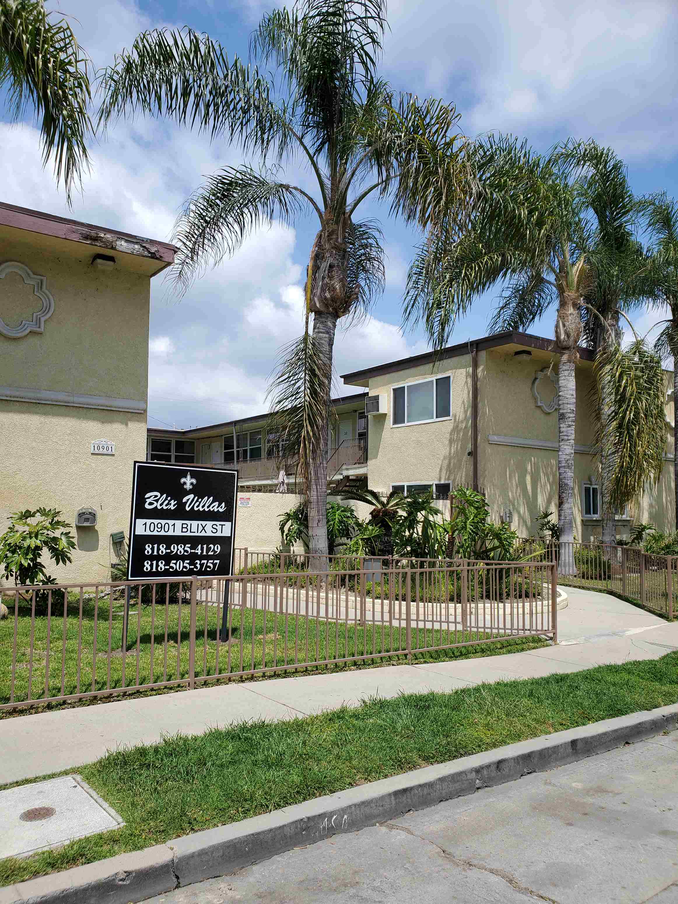 a house with palm trees and a sign in front of it