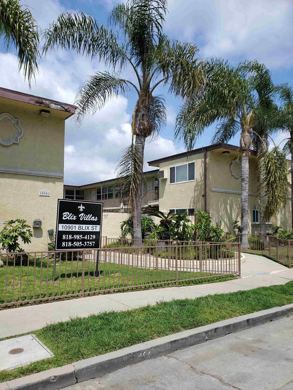 a house with palm trees and a sign in front of it