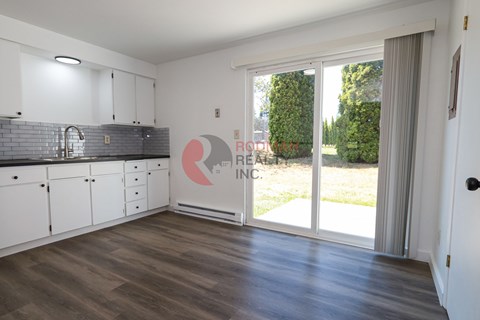 A kitchen with white cabinets and a grey backsplash.