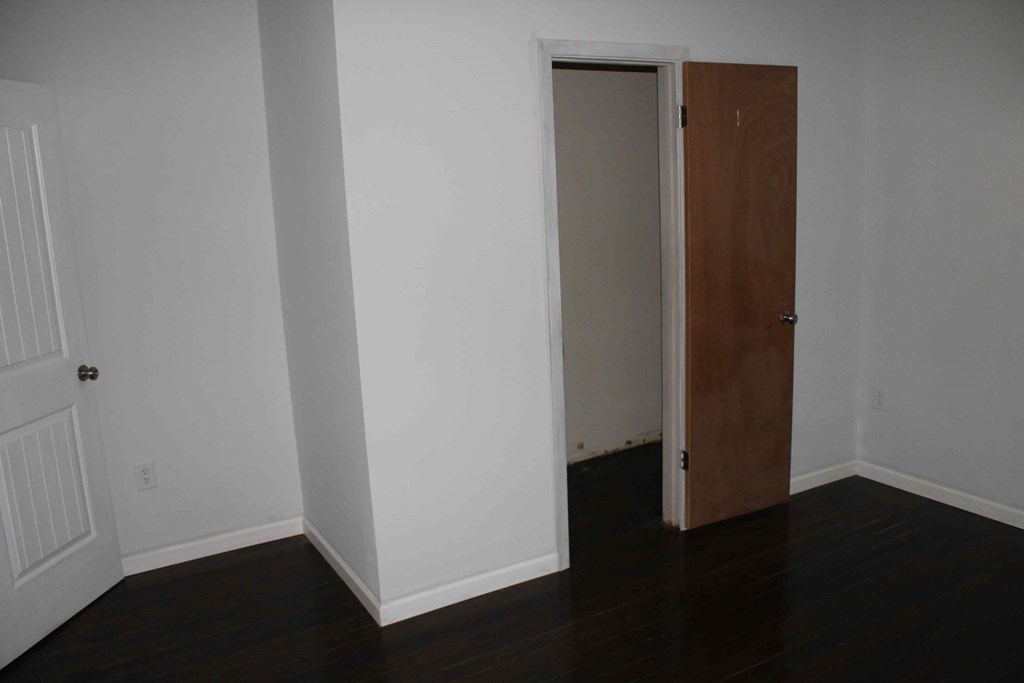 an empty room with a door open to a closet
