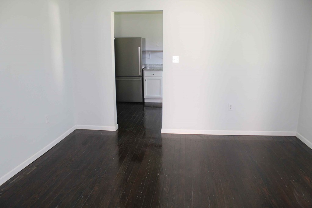 a living room with a hard wood floor and a refrigerator