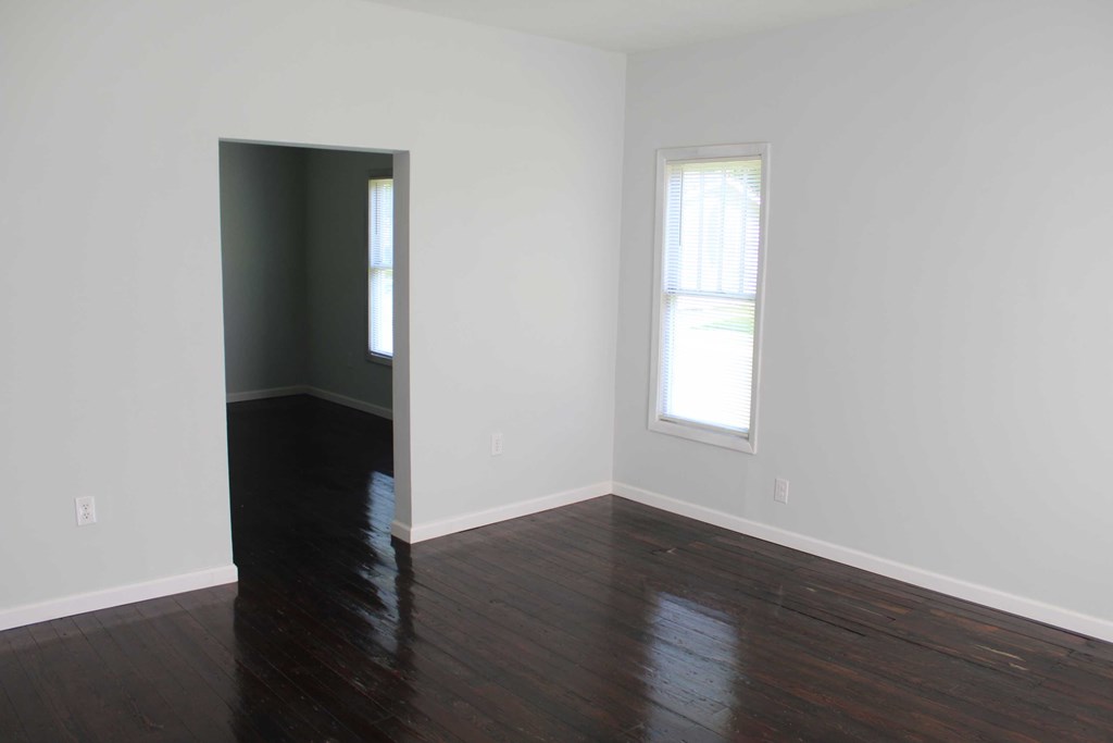 an empty living room with hard wood floors and a window
