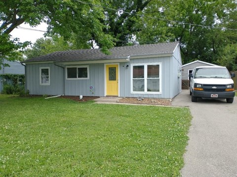 a blue house with a yellow door and a truck parked in the driveway