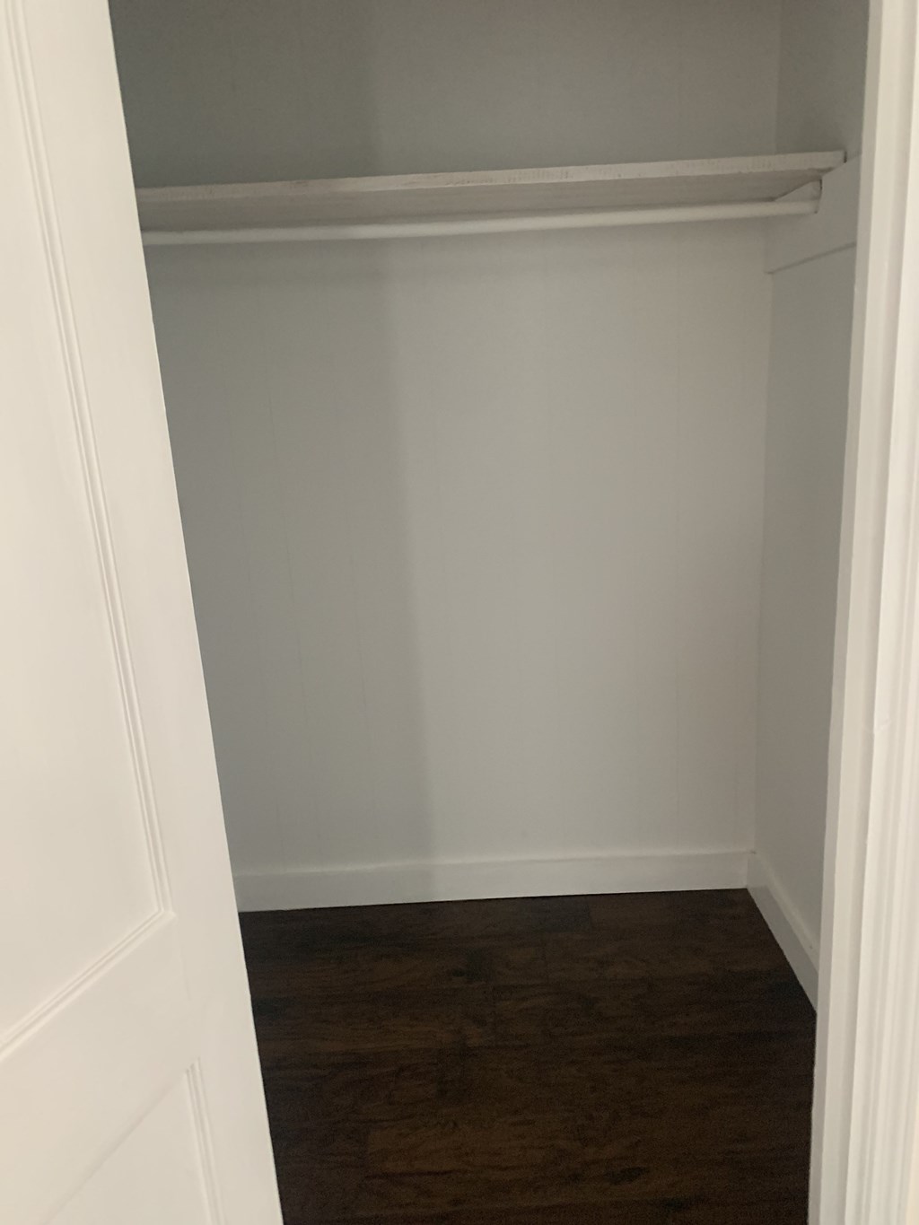 an empty closet with a wood floor and white walls