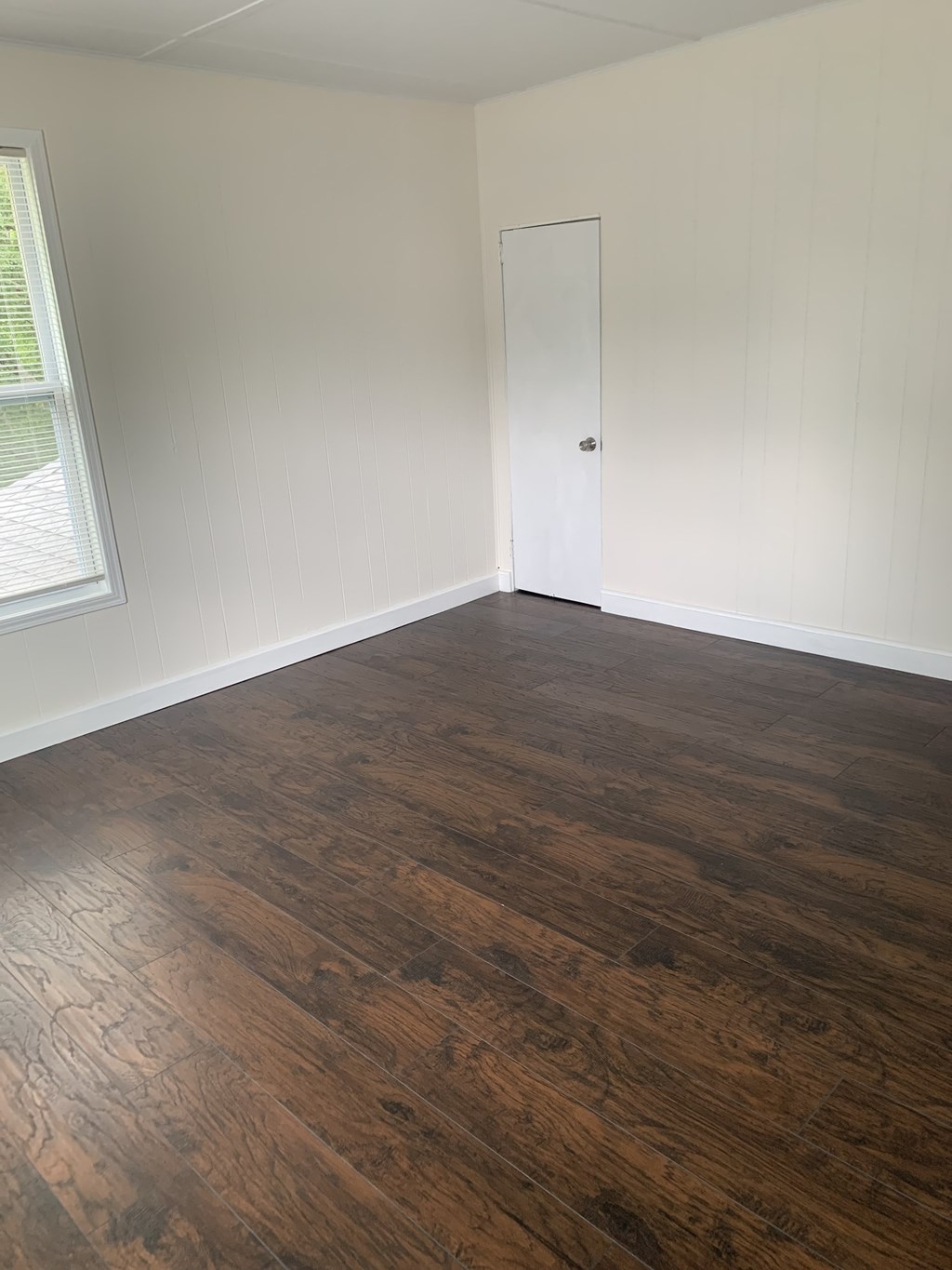 an empty living room with wood flooring and a door