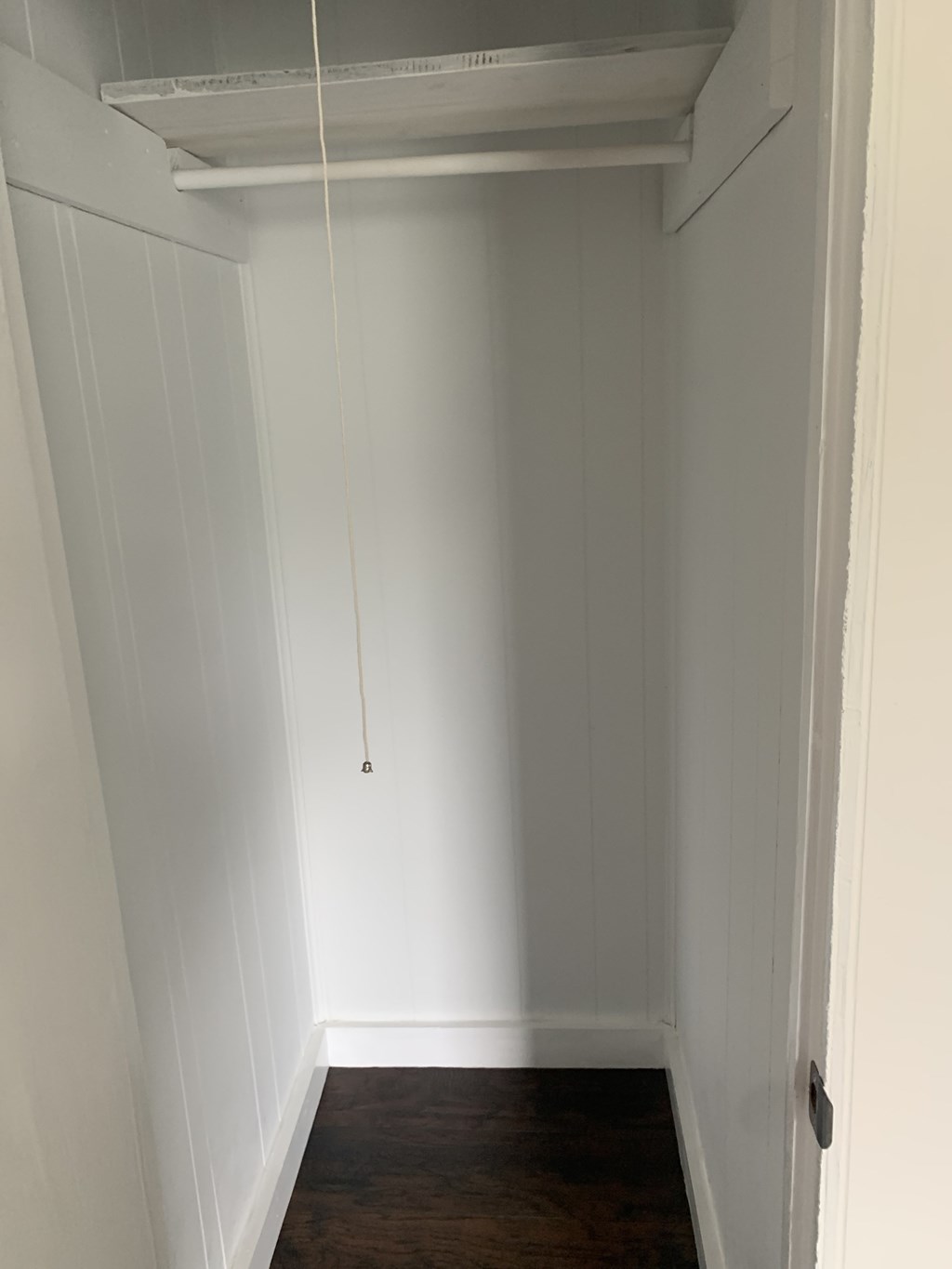 a small closet with white walls and a door with a hanging light