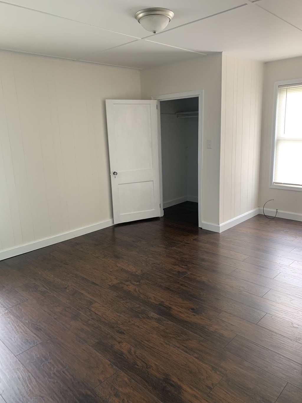 an empty living room with wooden floors and a white door