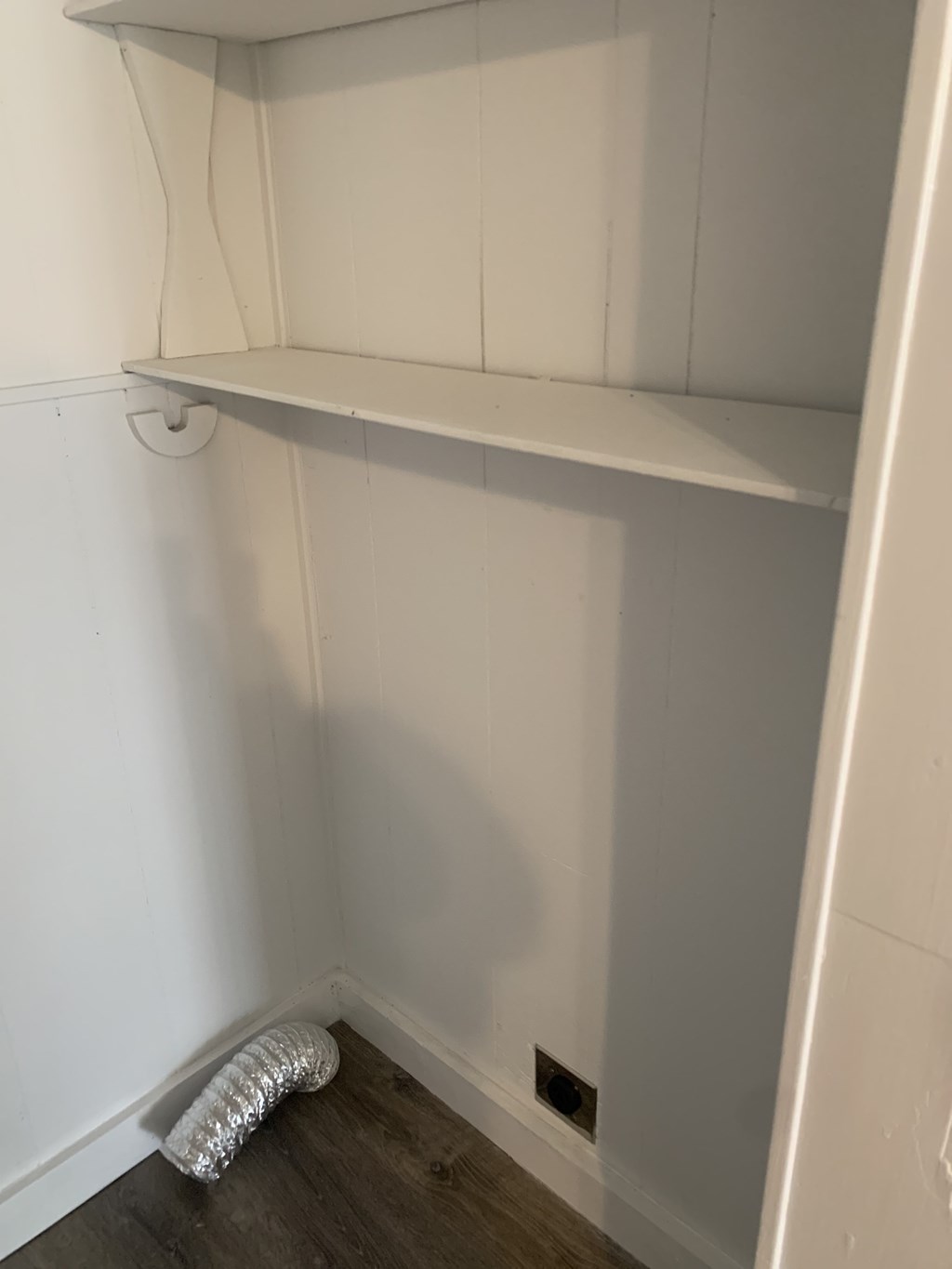 a small closet with a white wall and a shelf