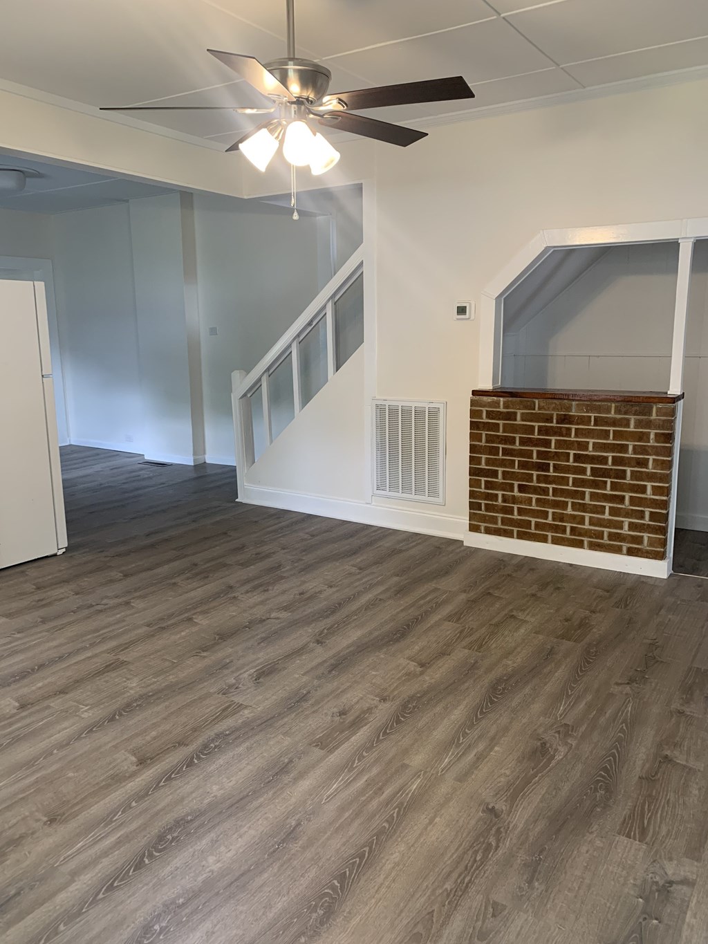 an empty living room with wood floors and a ceiling fan