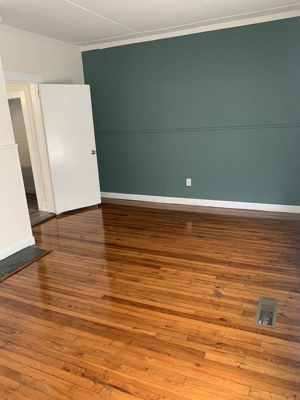 an empty living room with wood floors and green walls