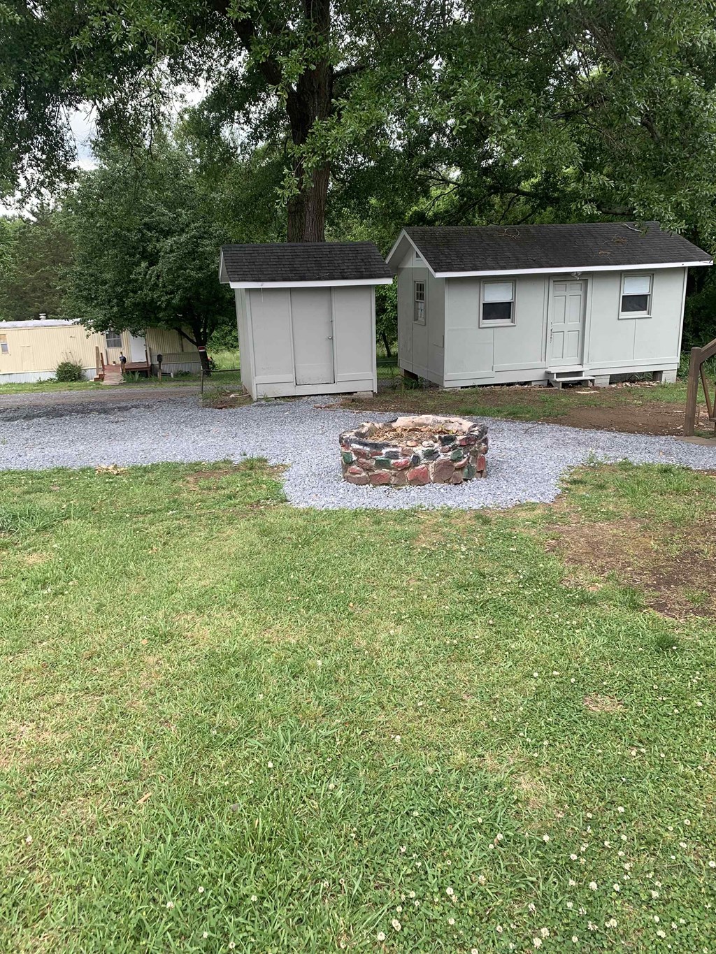 a backyard with a fire pit and two sheds