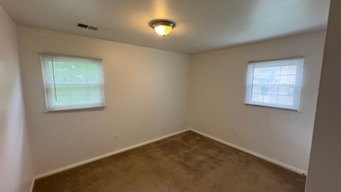 a bedroom with a carpeted floor and two windows