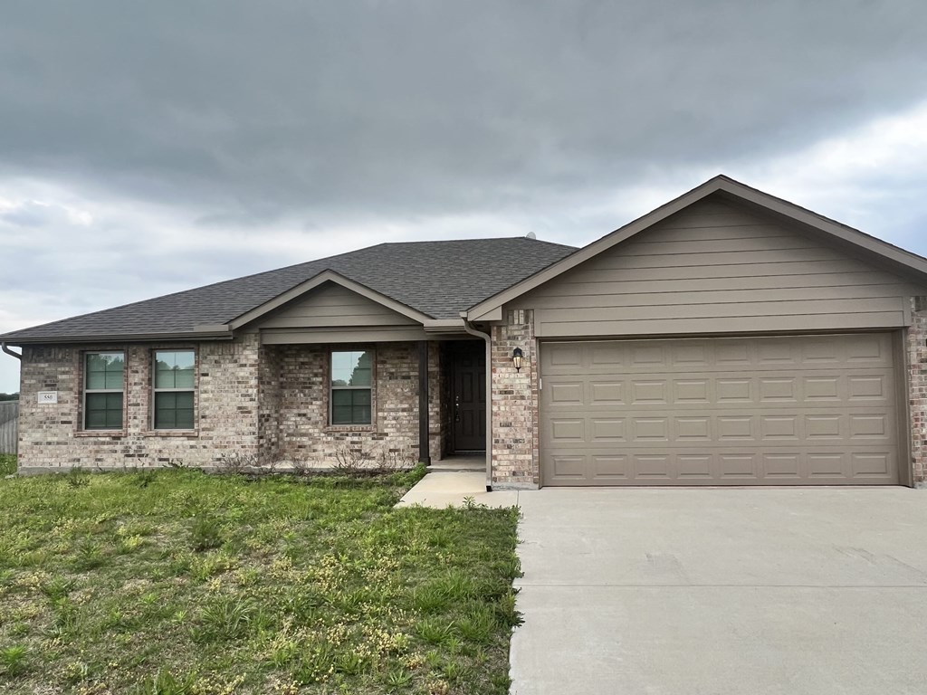 a brown house with a garage door on a cloudy day