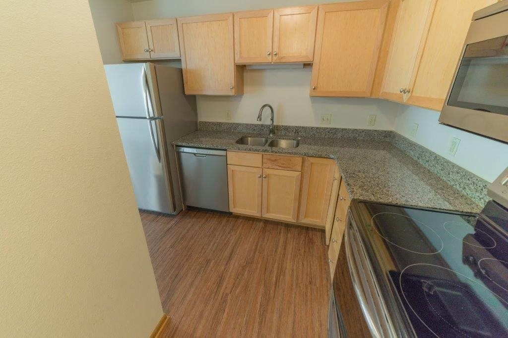 a kitchen with wooden cabinets and a stainless steel refrigerator