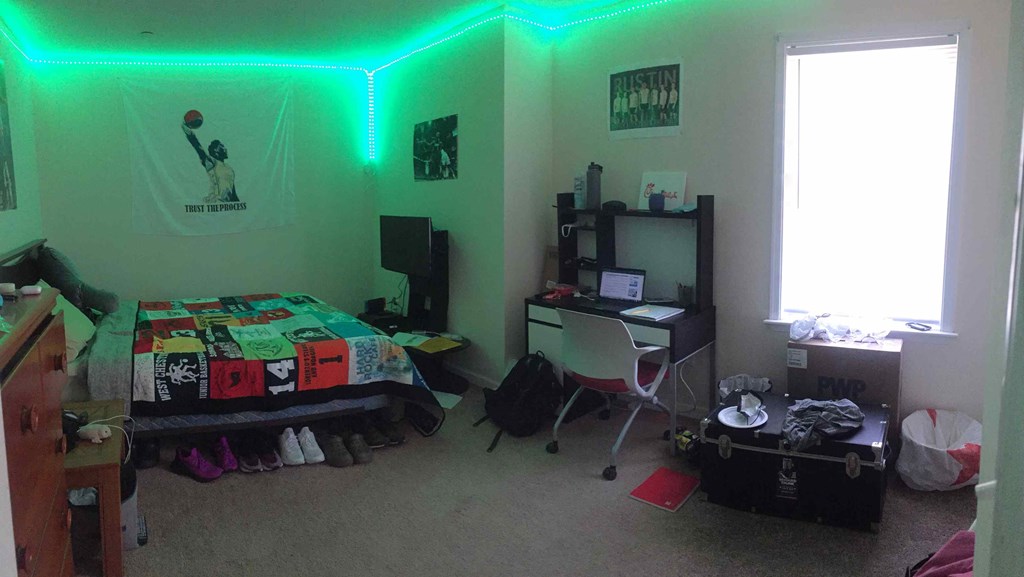 a bedroom with a bed and a desk and a green light on the ceiling