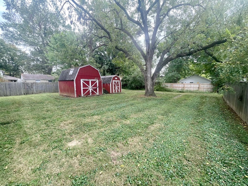 A red barn with a white cross is in the foreground of a grassy field.