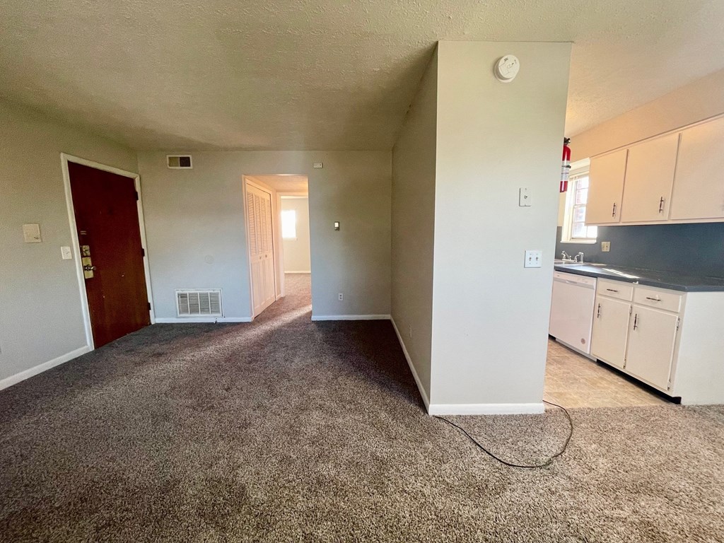 A room with a carpeted floor and a door on the left side.