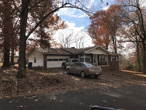 A silver car is parked in front of a house.