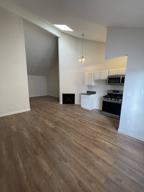 an empty living room and kitchen with wood flooring
