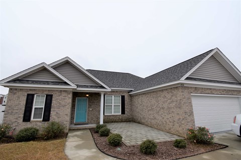 a brick house with a blue door and a driveway