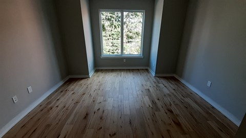 an empty room with wooden floors and a window