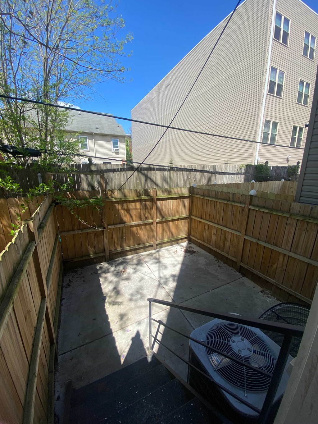 a backyard patio with a grill and a wooden fence