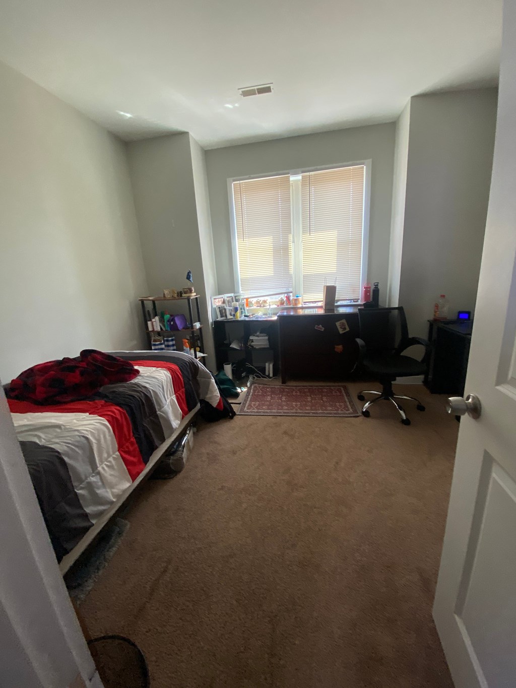 a bedroom with a bed and a desk and a window