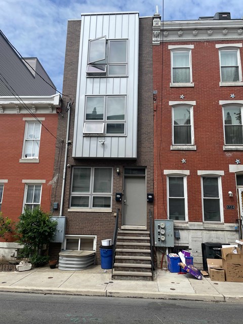 the front of an apartment building with stairs and a door
