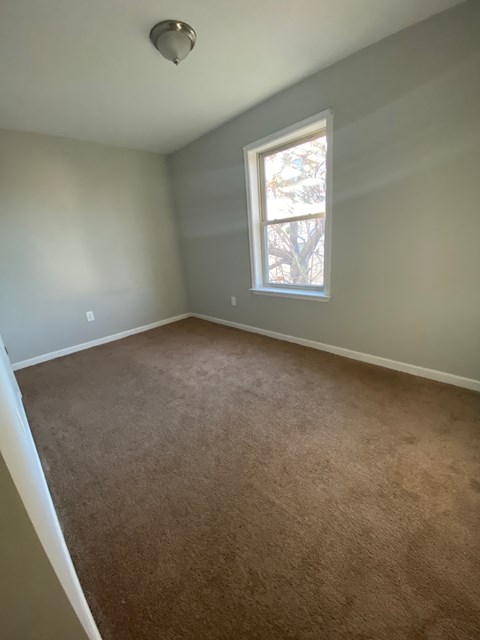 an empty room with a window and carpet