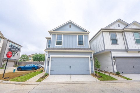 A two-story house with a garage and a stop sign in front.