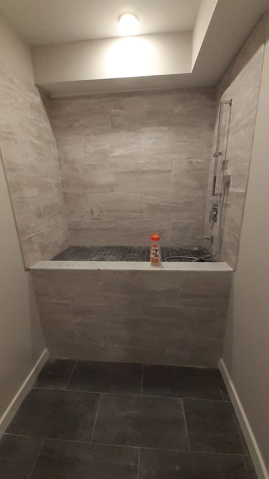 a large tiled shower with a tub and a shower head in a bathroom
