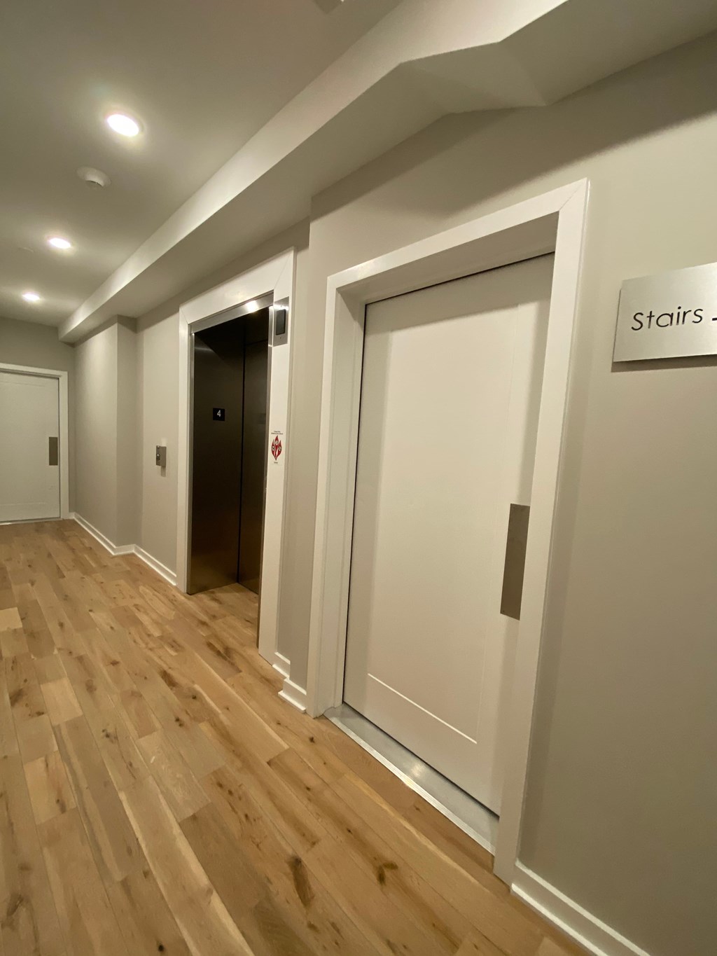 a hallway with white walls and wooden floors and a large white door