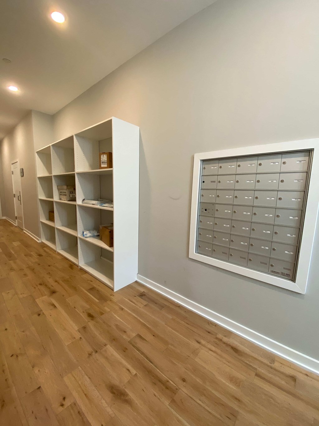 a room with a wall with shelves and a window and a wooden floor
