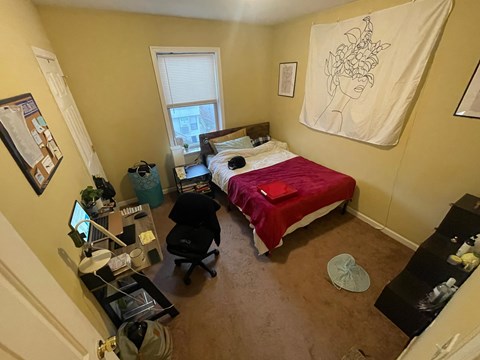 a bedroom with a bed and a desk and a window