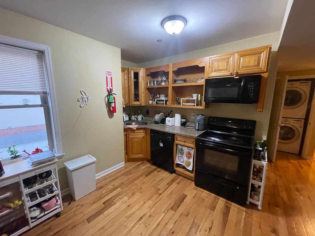 a kitchen with wooden floors and a black stove and a window