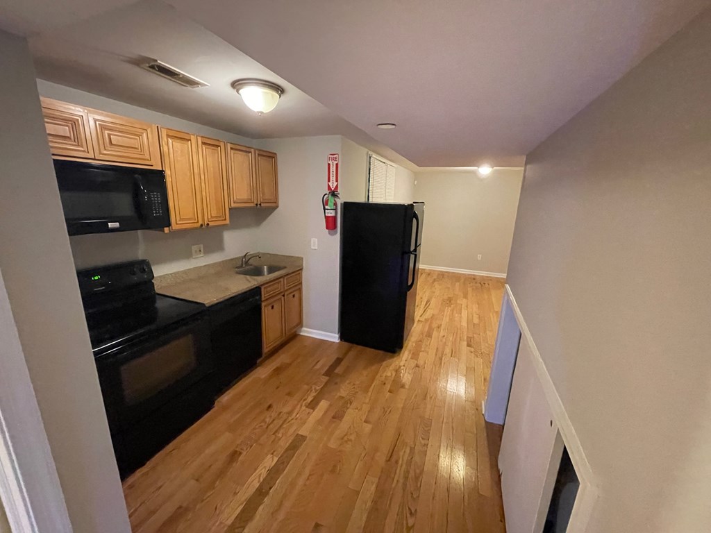 a kitchen with black appliances and wood floors