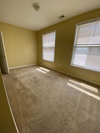 an empty room with two windows and a door
