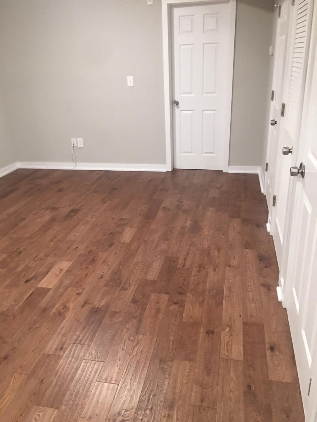a living room with a wooden floor and a white door