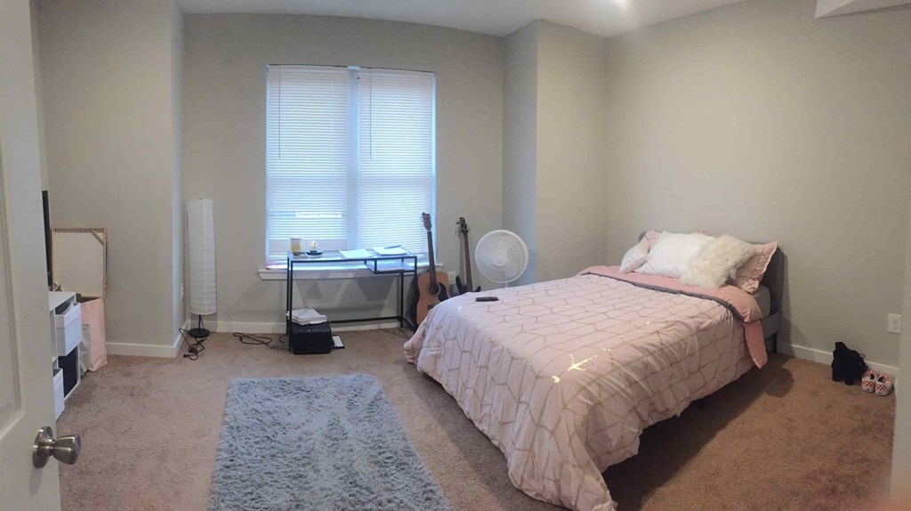 a bedroom with a bed and a desk and a window