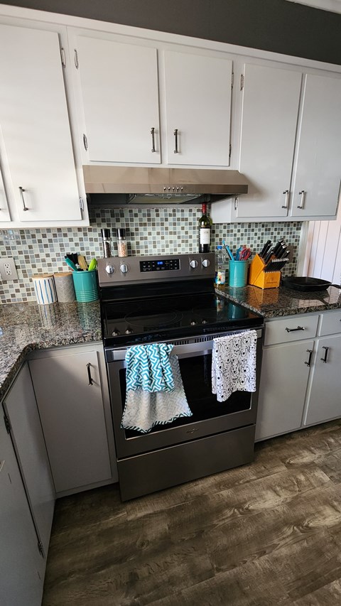 A kitchen with a black stove top oven and white cabinets.